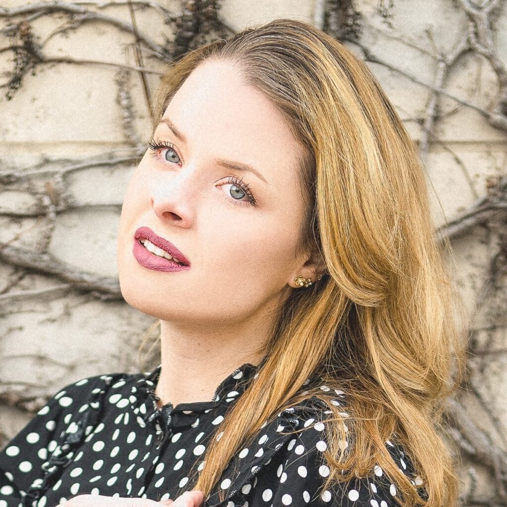 A circular profile close up image of Maddie, wearing a black and white polka dot dress, with dark blonde hair and a soft distant gaze toward the camera. Founder of La Vie Bien.