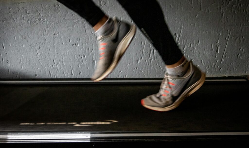 A stock image of a person in athletic shoes running on a treadmill.