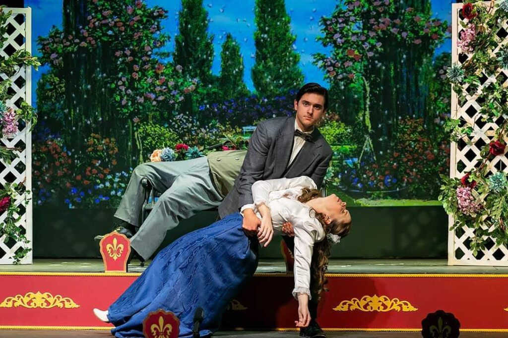 An image of the theatrical production "A Gentleman's Guide to Love and Murder" with Maddie, playing Phoebe, who has fainted in Monty's arms (played by Graham). 