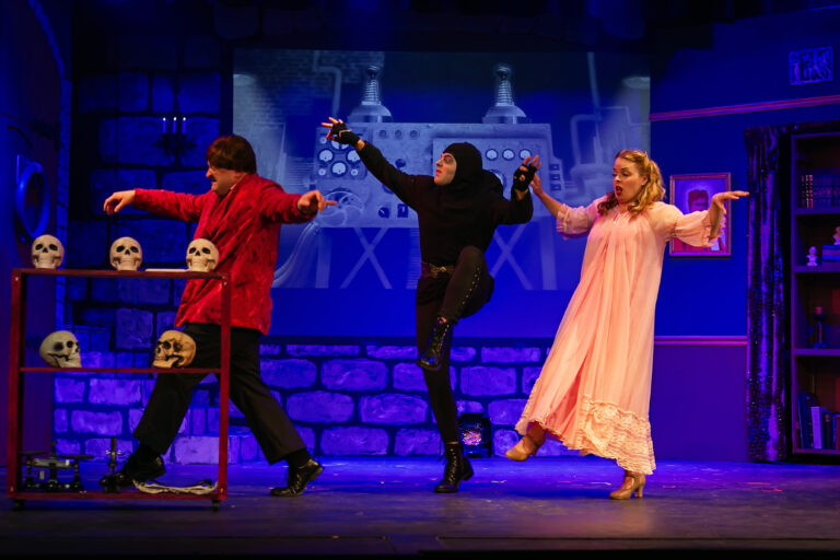 An image of the characters in the stage play Young Frankenstein, sneaking around on tiptoe. From Left to Right are Frederick Frankenstein, Igor, and Inga.